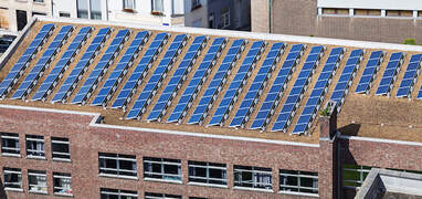 Large array of solar panels on top of a multi-story brick office building in downtown Sacramento, CA.